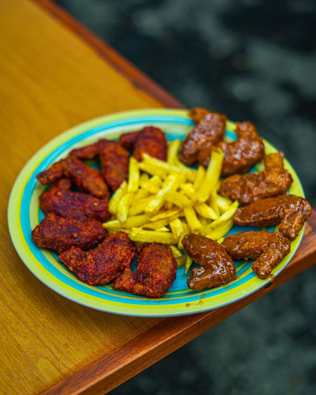 Wings Mixxa — saucy and dry chicken wings served with chips on a colourful plate at Kaka's Barbecue