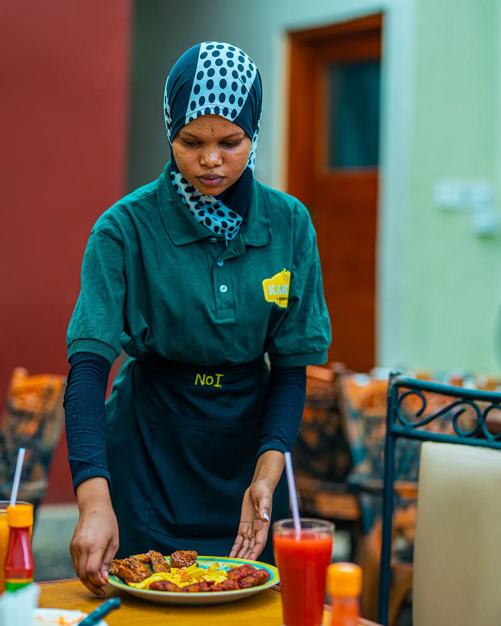 A Kaka's Barbecue waitress serving a fresh plate of food with a fresh juice